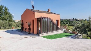 Un edificio moderno con techo inclinado, ventanas amplias y un área verde con césped.