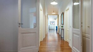 Um corredor com piso de madeira, portas brancas e uma luminária no teto.