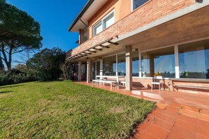 Moderni talo, jossa on katettu terassi, suuret ikkunat ja hyvin hoidettu nurmikko.