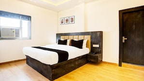 A modern bedroom with a large bed, a window, and a door. - Super Deluxe Room OYO Balua Road (Varanasi)