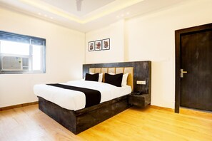 A modern bedroom with a large bed, a window, and a door. - Super Deluxe Room OYO Balua Road (Varanasi)