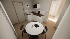 A compact kitchen with a white table, black chairs, a microwave, and a sink. - Urban Style Appart Home Up (Beaucé)