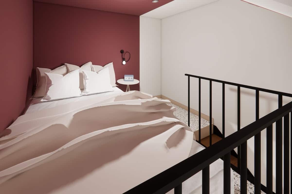 A bedroom with a bed, pillows, a nightstand, a wall clock, and a staircase with a black railing.