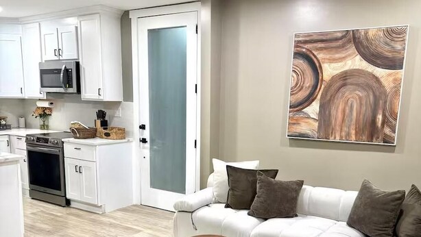 A modern living room with a sofa, a coffee table, and a kitchen in the background. - Walk to DPAC + Bulls - Chic Downtown Durham condo (Durham)