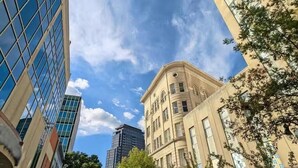 A street view with modern buildings, including a glass skyscraper and a classical building with arched windows. - Walk to DPAC + Bulls - Chic Downtown Durham condo (Durham)