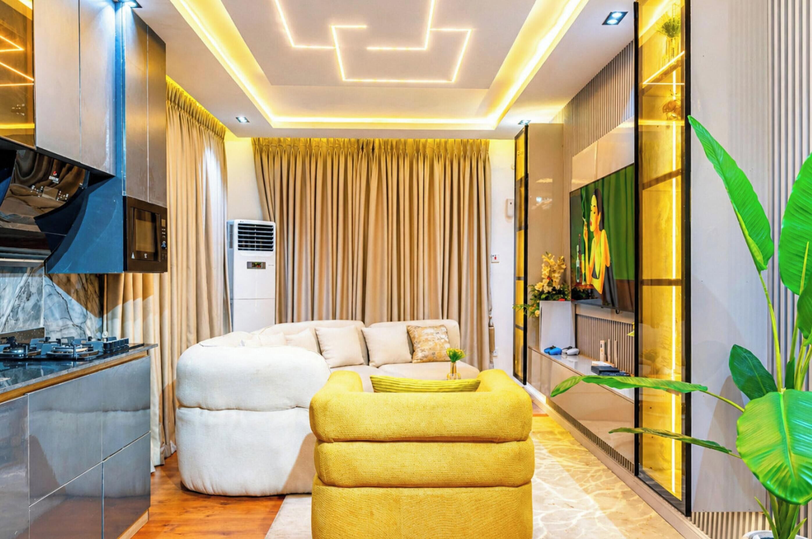 Una sala de estar moderna con sofá, reposapiés y televisor de pantalla plana.
