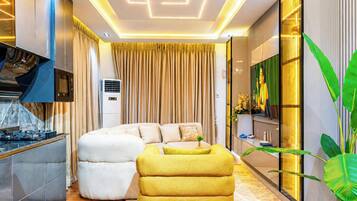 Una sala de estar moderna con sofá, reposapiés y televisor de pantalla plana.