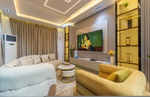 Een moderne woonkamer met een bank, een salontafel, een televisie en een decoratieve plank.