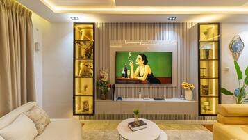 Una sala de estar moderna con un televisor de pantalla plana, un sofá, una mesa de centro y estantes decorativos.