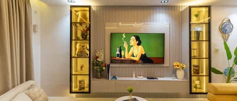 Uma sala de estar moderna com televisão de tela plana, sofá, mesa de centro e prateleiras decorativas.