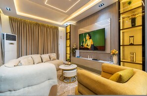 Ein modernes Wohnzimmer mit einer Couch, einem Couchtisch, einem Fernseher und einem dekorativen Regal.