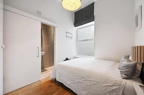 Ein Schlafzimmer mit Bett, Fenster, Tür und einer Lampe.