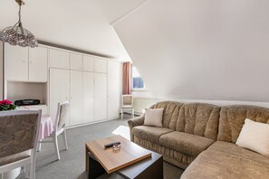 Uma sala de estar moderna com sofá, mesa de centro, televisão e área de jantar com cadeiras e mesa.