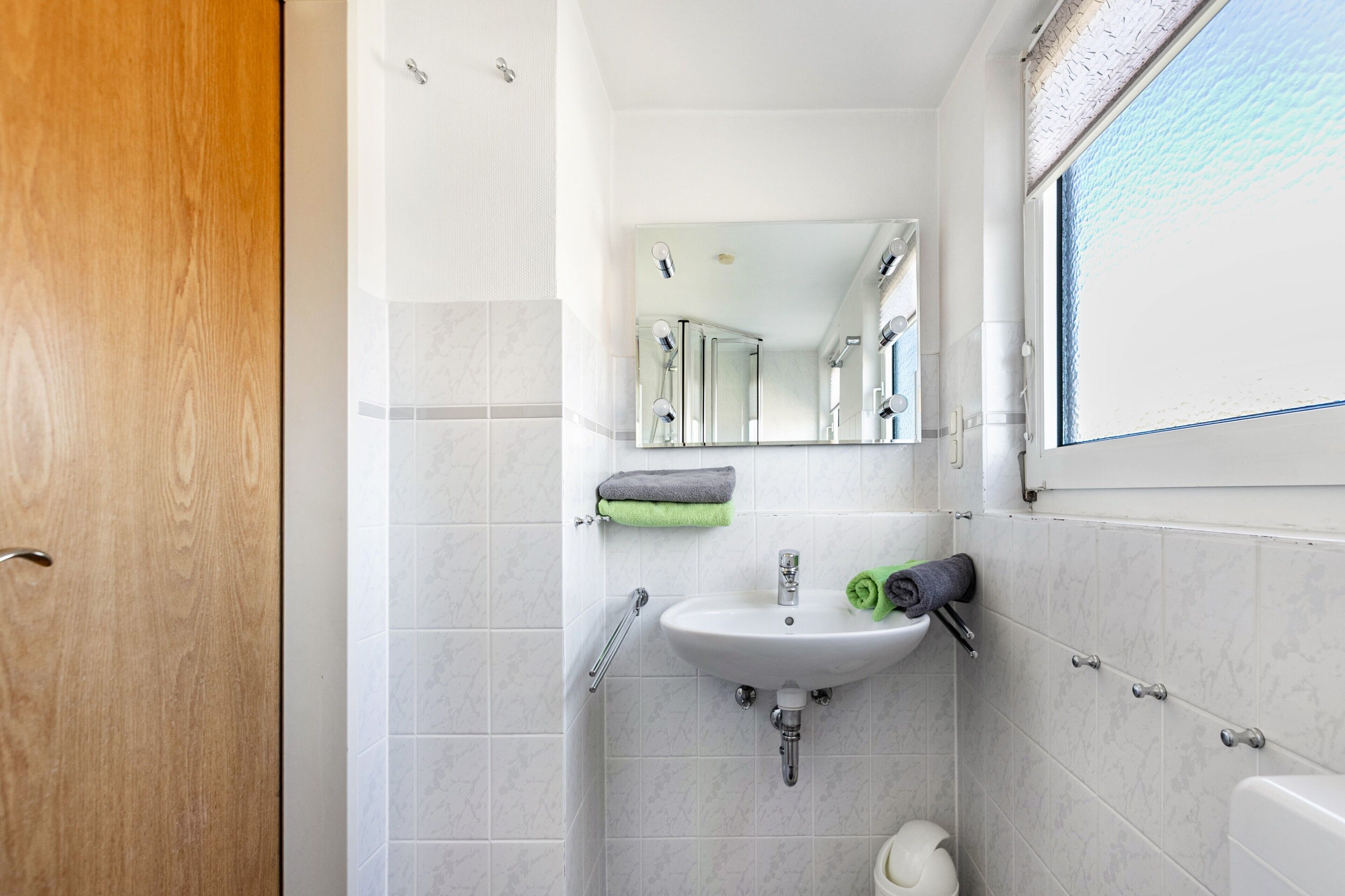 A bathroom with a sink, mirror, and towel rack.