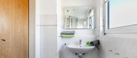 A bathroom with a sink, mirror, and towel rack.