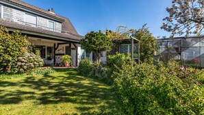 A residential property with a well-maintained garden, a covered porch, and a brick wall. - Apartment '3-Room Palmyra' with Balcony, Wi-Fi and Shared Garden (Büsum)