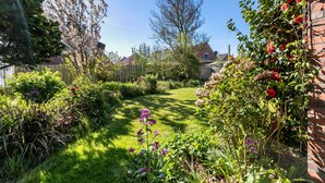 A well-maintained garden with a variety of plants and flowers, a clear pathway, and a wooden fence. - Apartment '3-Room Palmyra' with Balcony, Wi-Fi and Shared Garden (Büsum)