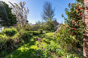 Een verzorgde tuin met diverse planten en bloemen, een duidelijk pad en een houten omheining.