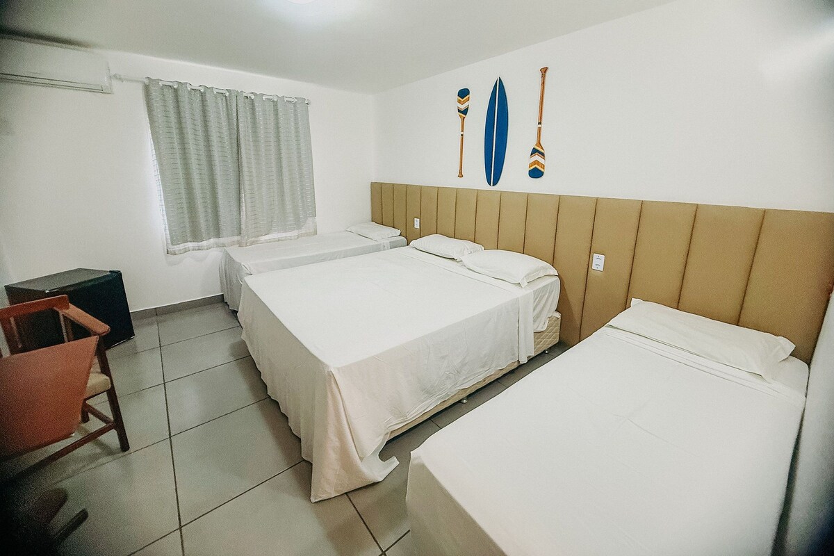 A hotel room with two beds, a window with curtains, a desk, and a chair.