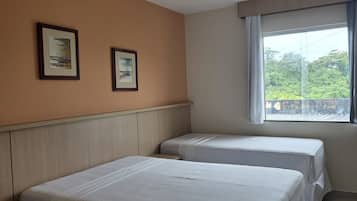 Habitación de hotel con dos camas, ventana con vistas y dos cuadros en la pared.