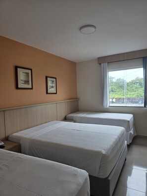 Habitación de hotel con dos camas, ventana con vistas y dos cuadros en la pared.