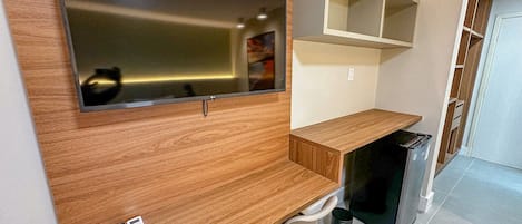 A modern kitchen with a built-in TV, wooden countertop, and a trash bin.