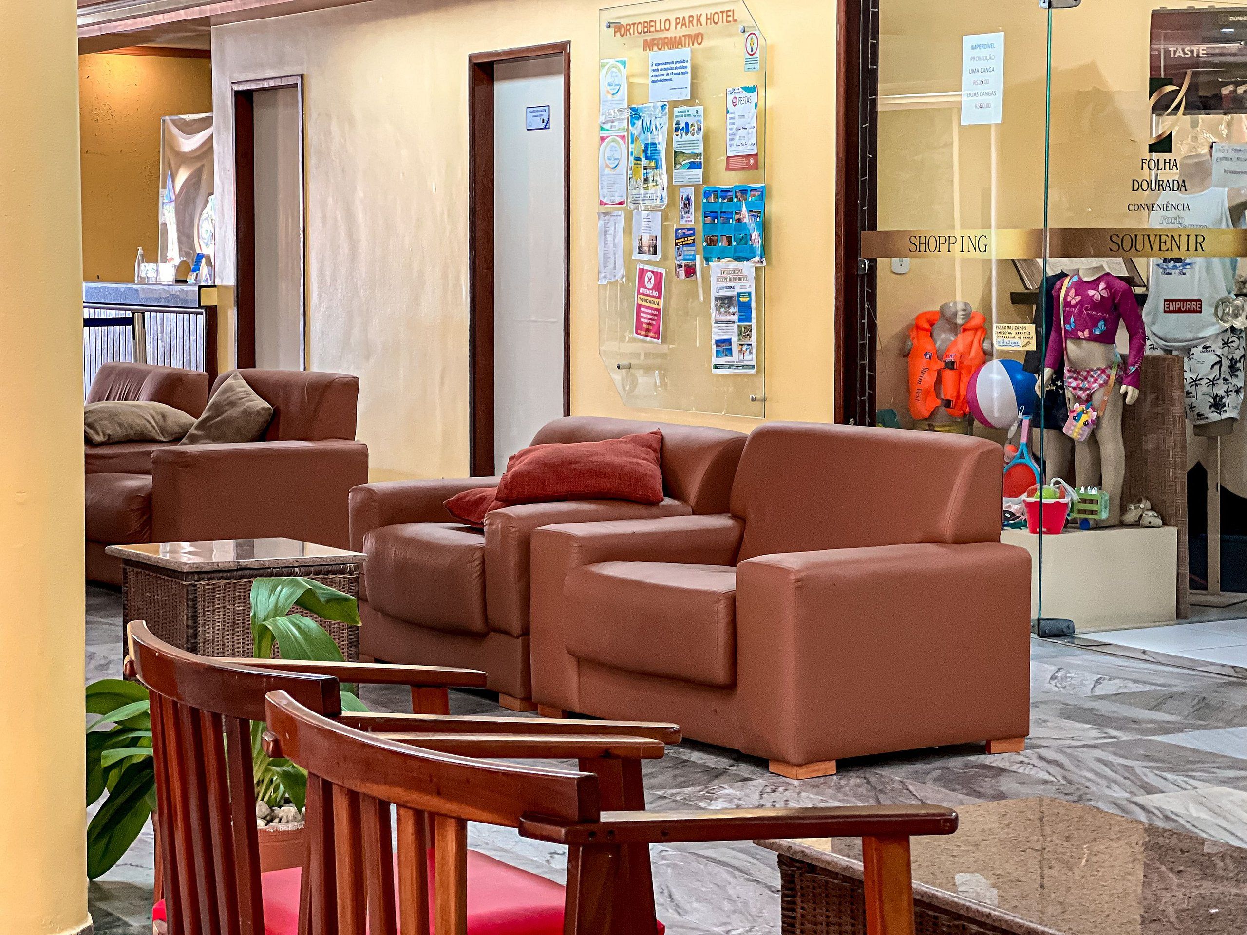 Eine Hotelhalle mit Ledersofas, einem Empfangsbereich und einer Glastür, hinter der Souvenirs ausgestellt sind.