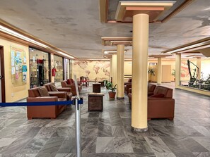 A hotel lobby with seating areas, a world map mural, and a glass storefront. - Porto Belo Park (Porto Seguro)