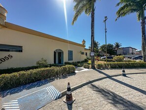A building with a number '2055' on its side, a clear sky, and a street with a pedestrian crossing. - Porto Belo Park (Porto Seguro)