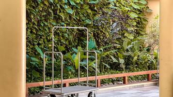 A cart with wheels in front of a wall covered with dense green foliage.