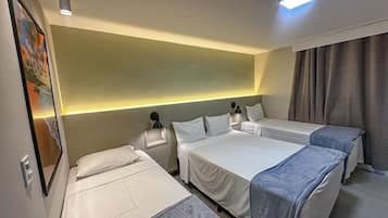 A hotel room with two single beds, a nightstand with a lamp, and a painting on the wall.