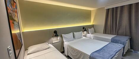 Una habitación de hotel con dos camas individuales, una mesita de noche con lámpara y un cuadro en la pared.