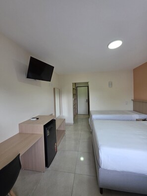 A hotel room with a desk, a television mounted on the wall, two beds, and a door leading to another room. - Porto Belo Park (Porto Seguro)