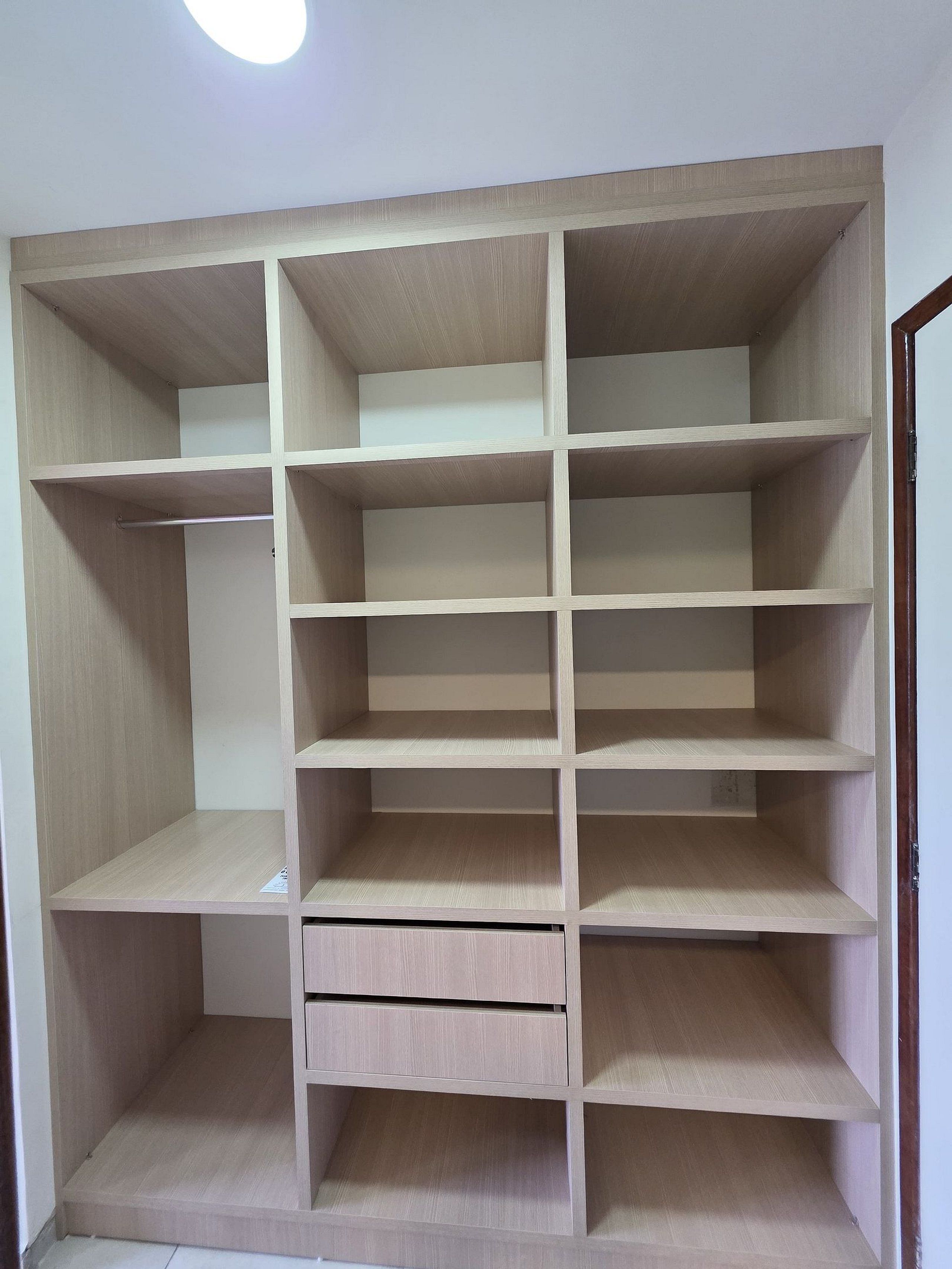 A wooden wardrobe with multiple compartments and drawers.