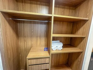 A wooden closet with open shelves, a hanging rod, and a small drawer unit. - Porto Belo Park (Porto Seguro)