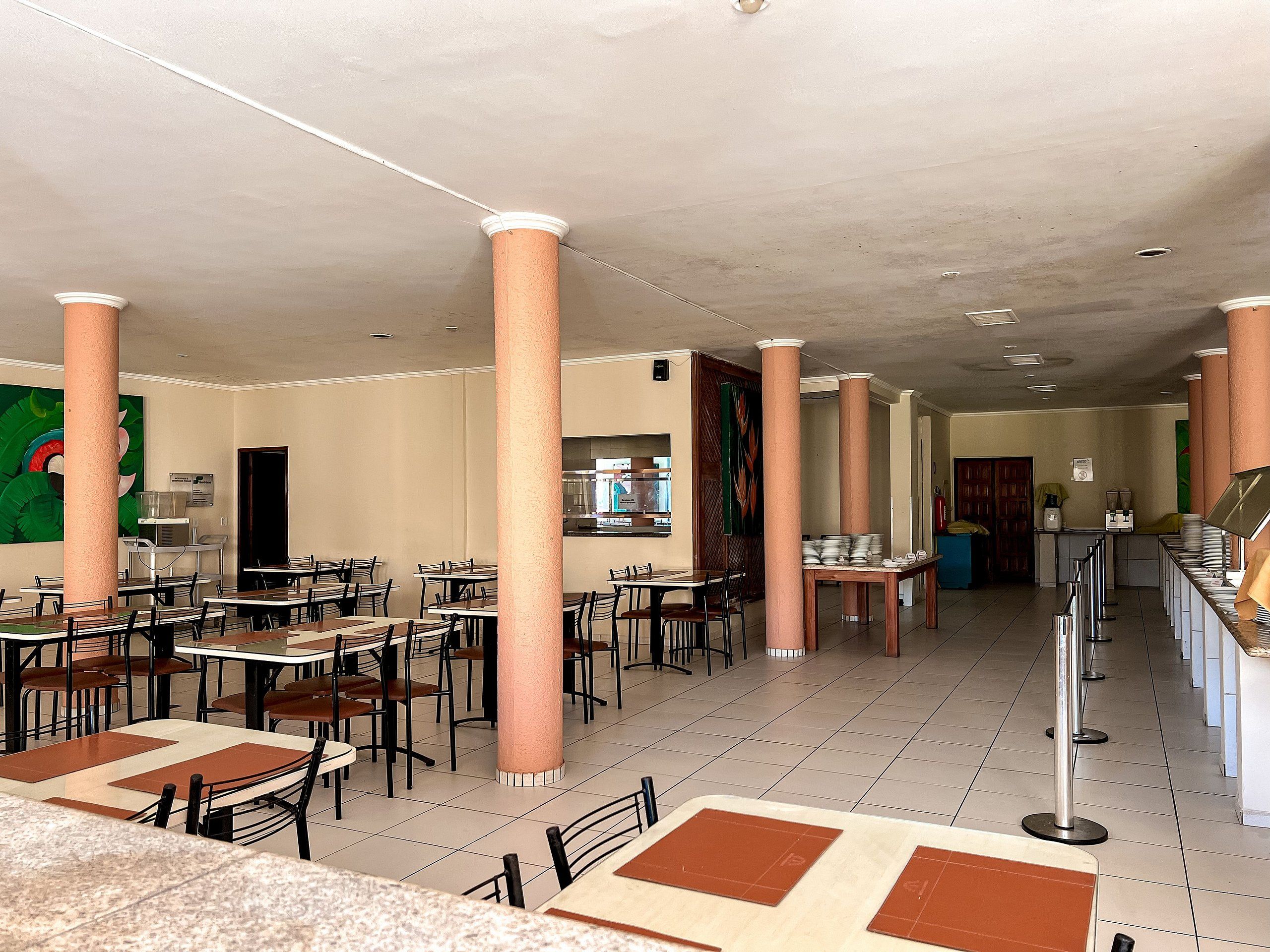 Un vaste espace intérieur comprenant plusieurs tables et chaises, un comptoir et une grande colonne.