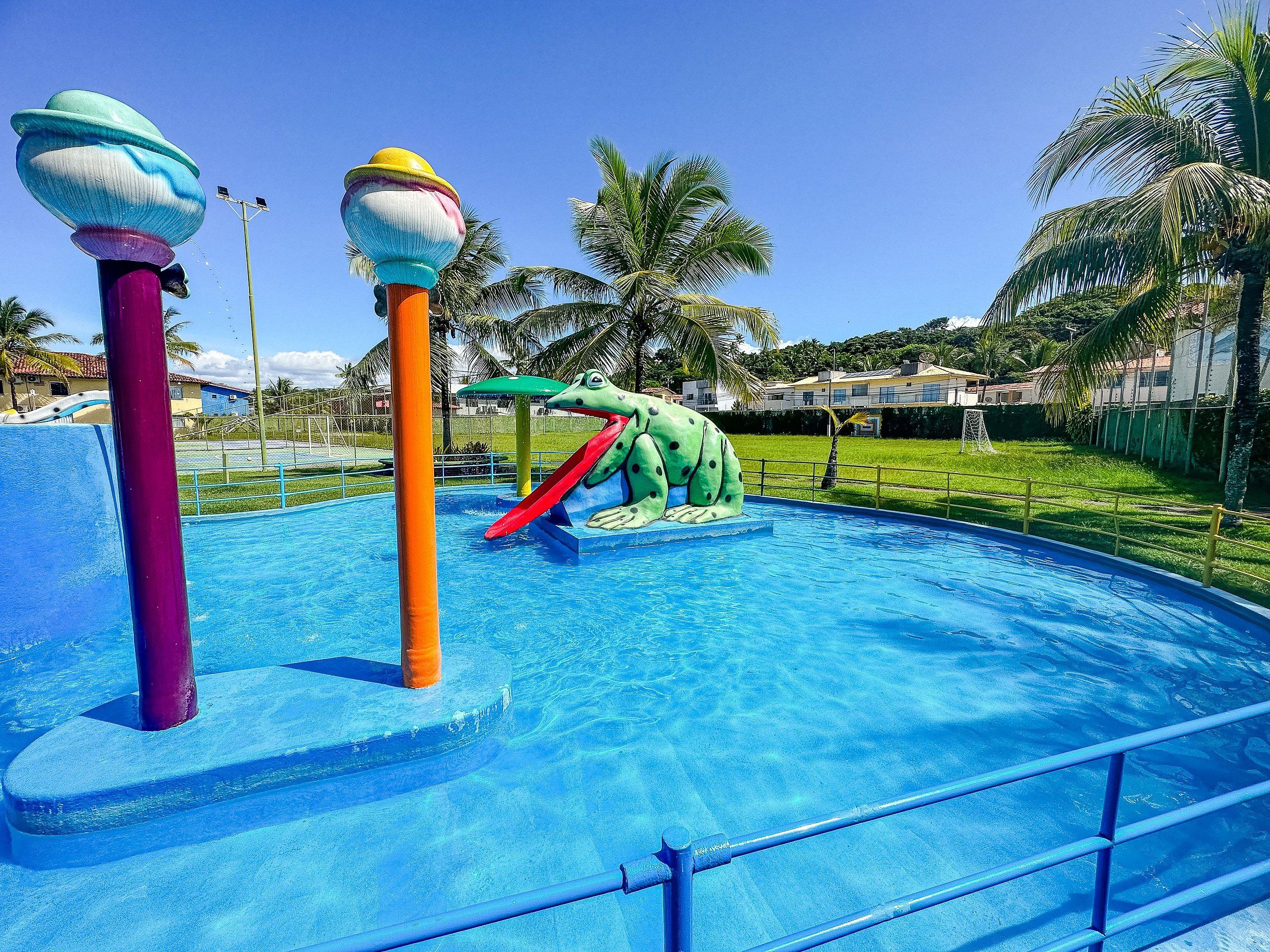 A swimming pool with a slide and a frog-themed water feature.