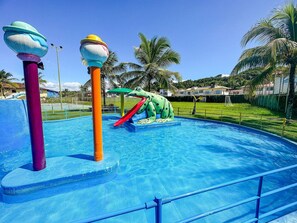 Une piscine avec un toboggan et une fontaine aquatique sur le thème des grenouilles.