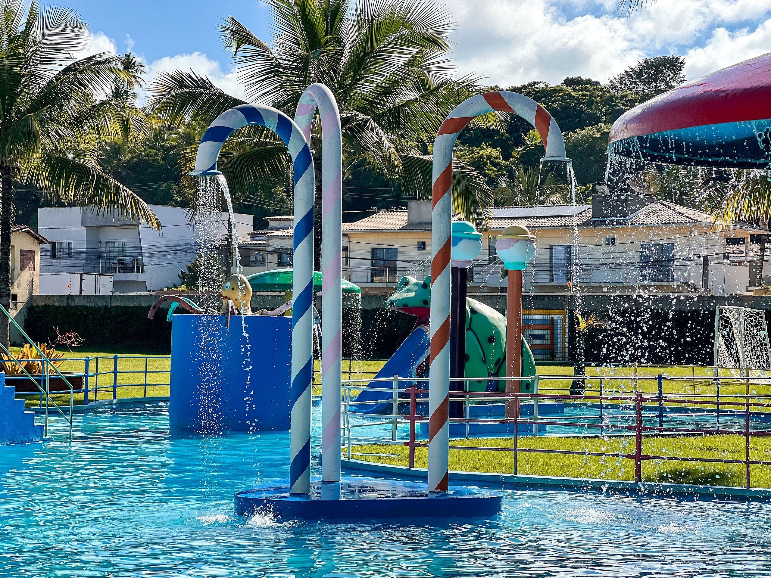 Piscina com elementos aquáticos, incluindo duas estruturas semelhantes a candy canes e um toboágua.
