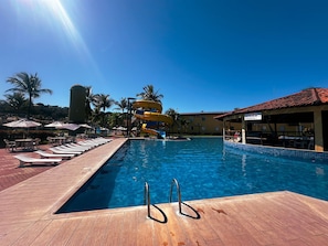 A swimming pool with a water slide, lounge chairs, and umbrellas. - Porto Belo Park (Porto Seguro)
