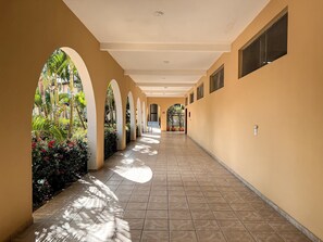 A corridor with arches, potted plants, and tiled flooring. - Porto Belo Park (Porto Seguro)