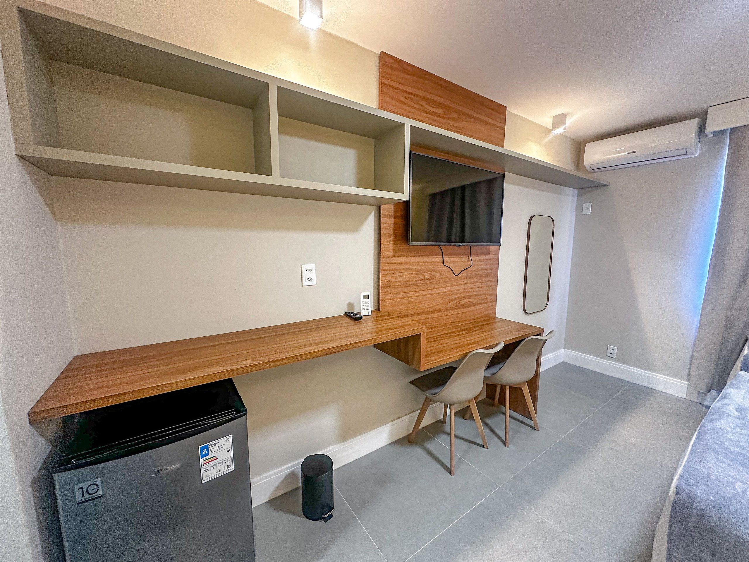 A compact kitchenette with a built-in trash bin, a small refrigerator, and a microwave.