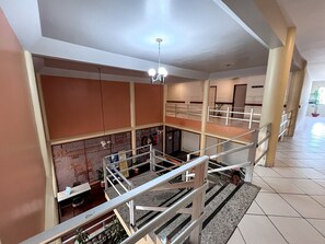 A multi-level interior with a staircase, railings, and a ceiling light fixture. - Porto Belo Park (Porto Seguro)
