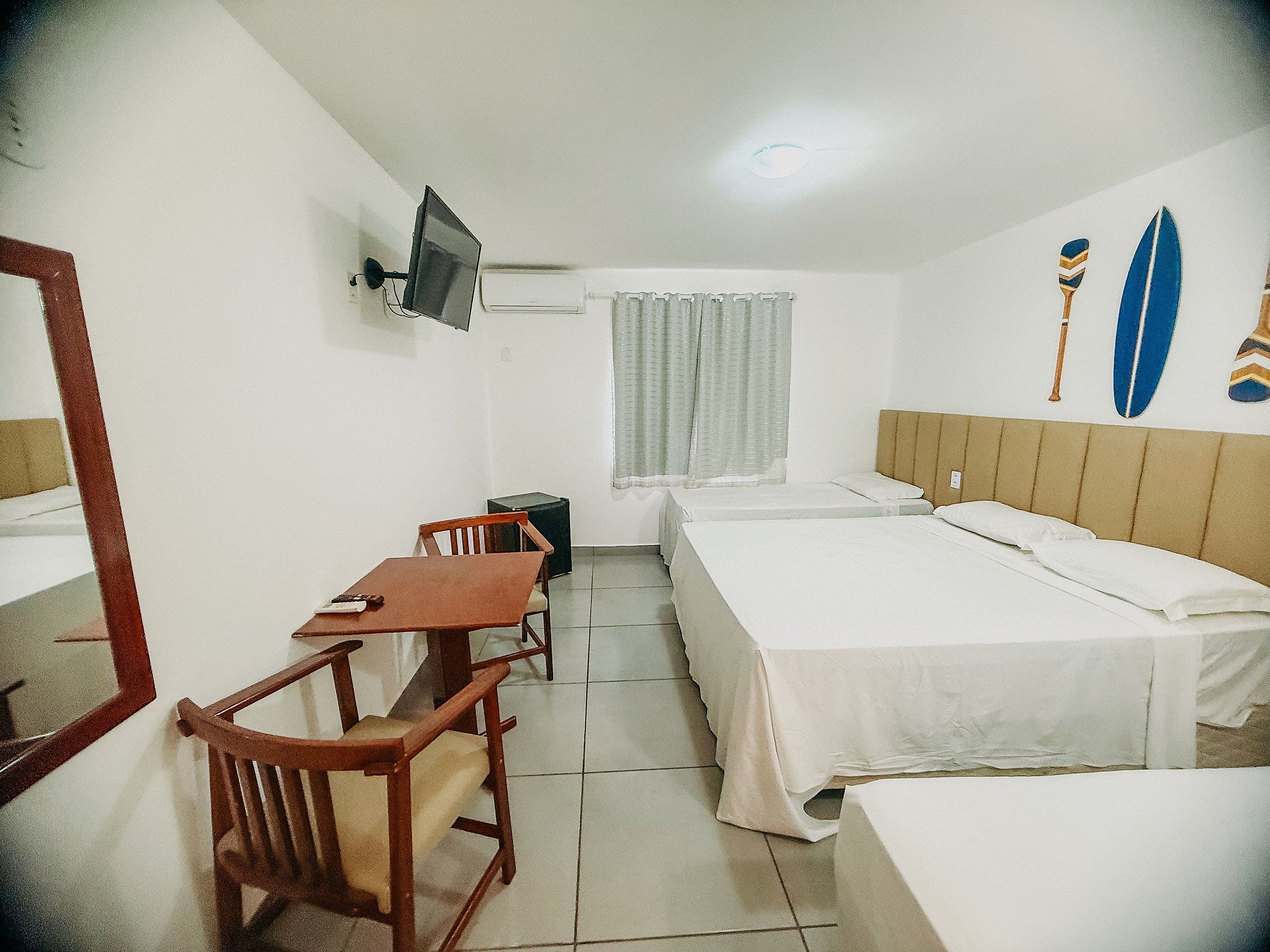 A hotel room with a bed, a desk, a chair, a television, and a window with curtains.