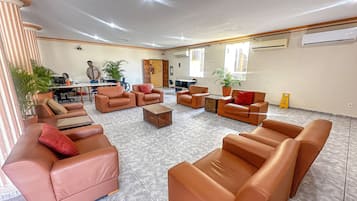Tilava aula, jossa on nahkasohvia, sohvapöytä ja ruukkukasveja.