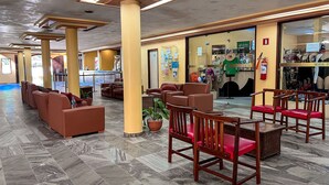 A hotel lobby with seating areas, a reception desk, and a shop. - Porto Belo Park (Porto Seguro)