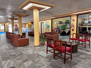 Un hall de hotel con áreas de estar, una recepción y una tienda.