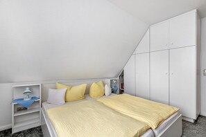 Ein Schlafzimmer mit einem Bett, einem weißen Kleiderschrank und einem Nachttisch mit Lampe.