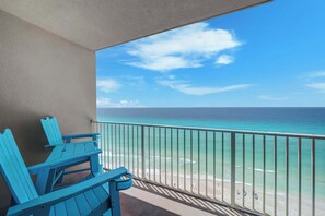 Ein Balkon mit Blick auf den Ozean, einem Geländer und zwei blauen Stühlen.