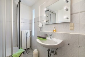 Une salle de bain avec une douche, un lavabo avec un miroir et un porte-serviettes.